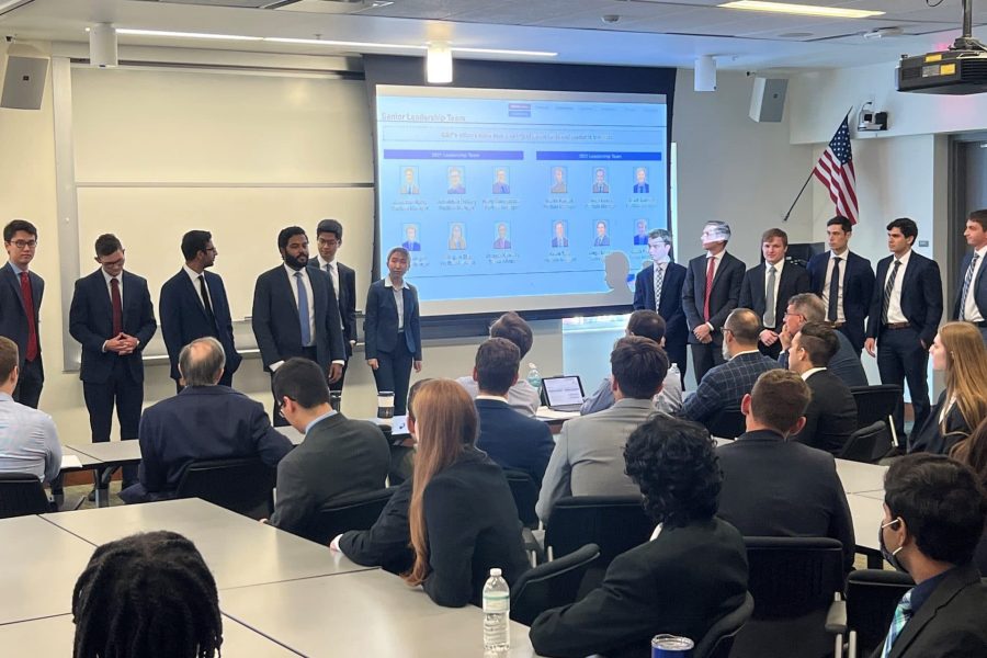 A large group of students stand at the front of a classroom giving a presentation to a large audience
