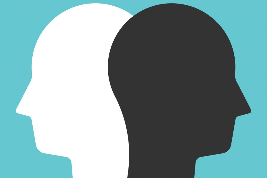 One white and one black head profile silhouettes facing opposite directions on turquoise background.