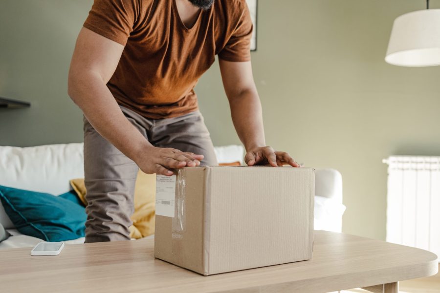 Young man boxing an online purchase on a coffee table.