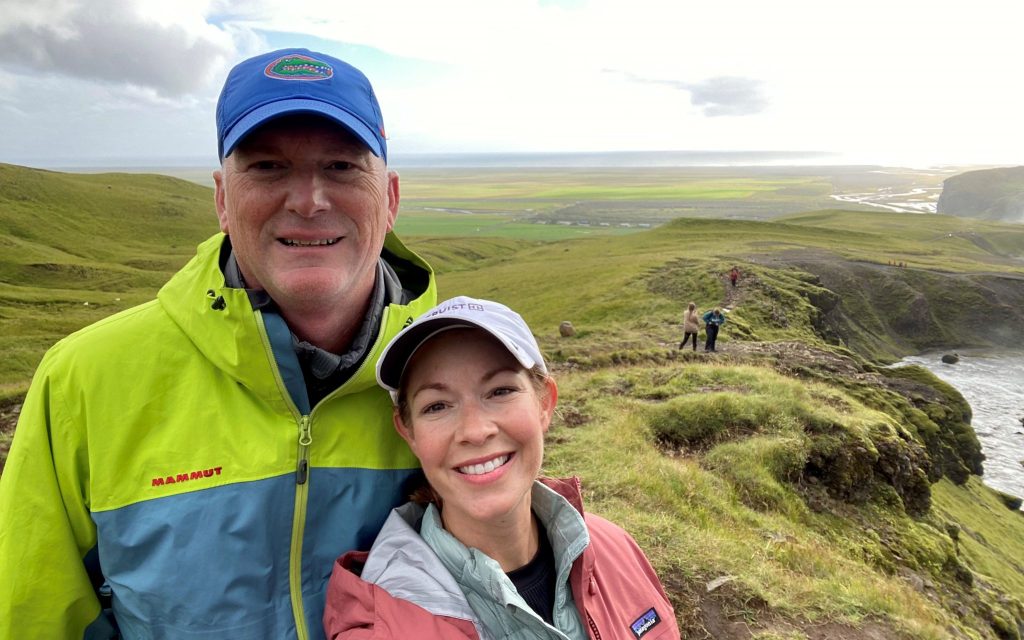 Katie Saez and a man pose for a selfie on a cliff while hiking.