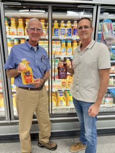 Matt McLean and his father holding bottles of Uncle Matt's juice in a grocery aisle.