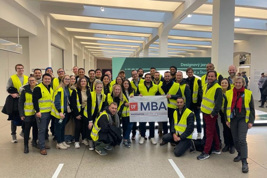 Students hold UF MBA sign and wear neon construction vests.