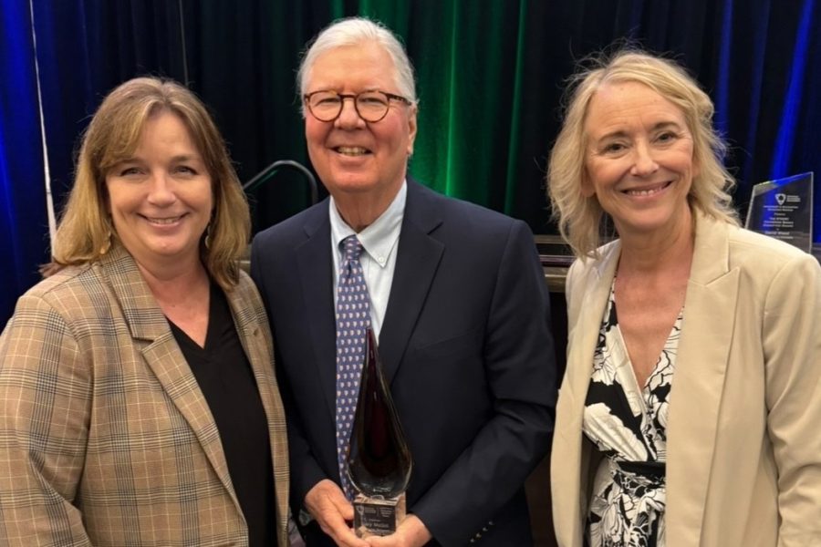 Gary McGill holding an award with two representatives from the American Accounting Association