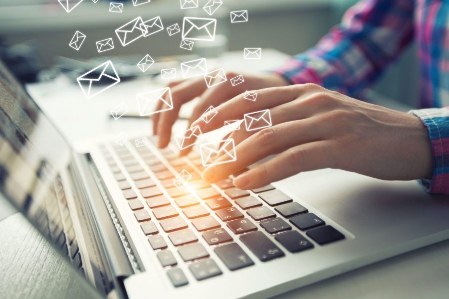 Business guy is sending the emails with laptop at work space.