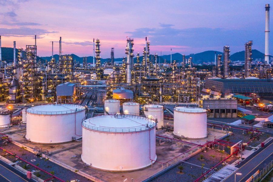 Aerial top view oil and gas chemical tank with oil refinery plant background at twilight.