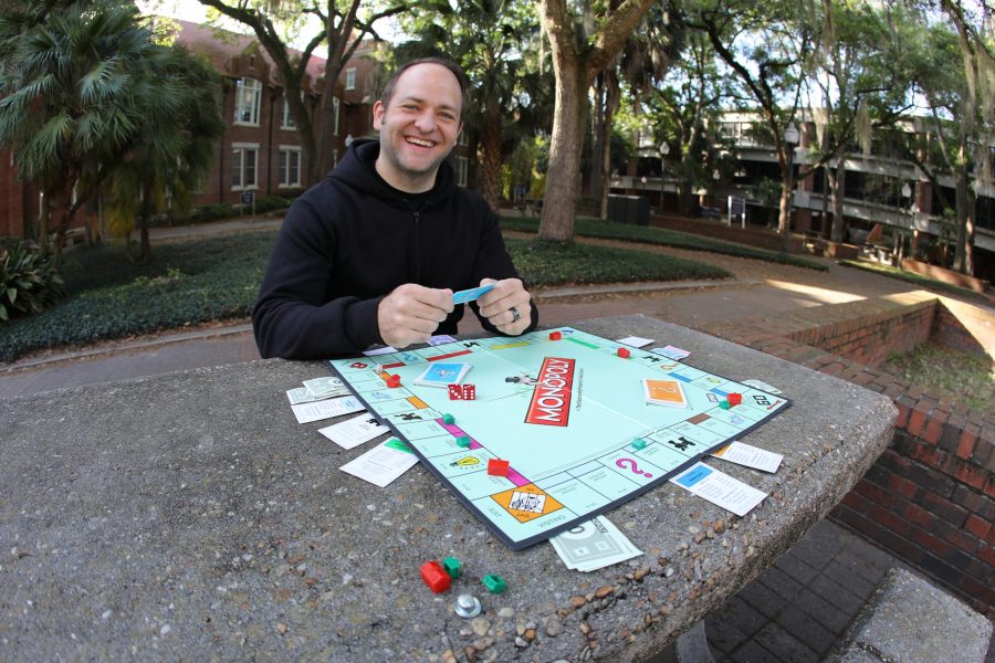 Paul Madsen sits behind a Monopoly board.