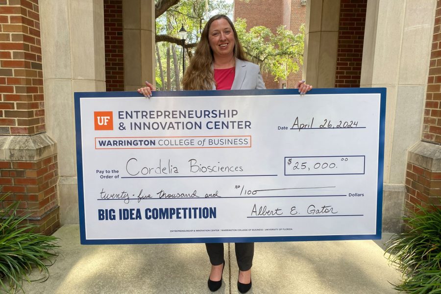 Co-founder of Cordelia Biosciences holds check for $25,000.