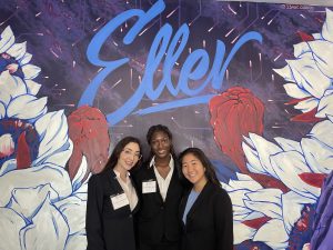 Students pose under Eller poster.