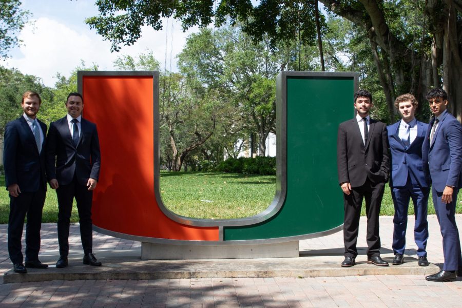 Students pose next to statue at University of Miami.