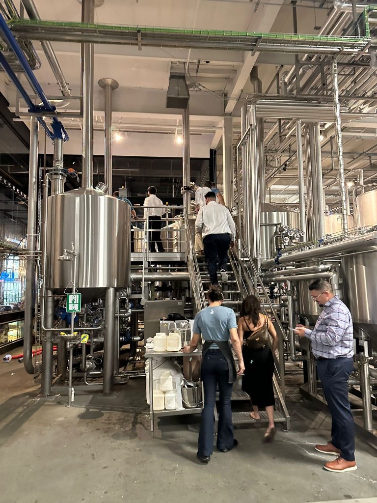 People walking around brewery equipment during a tour of a brewery.