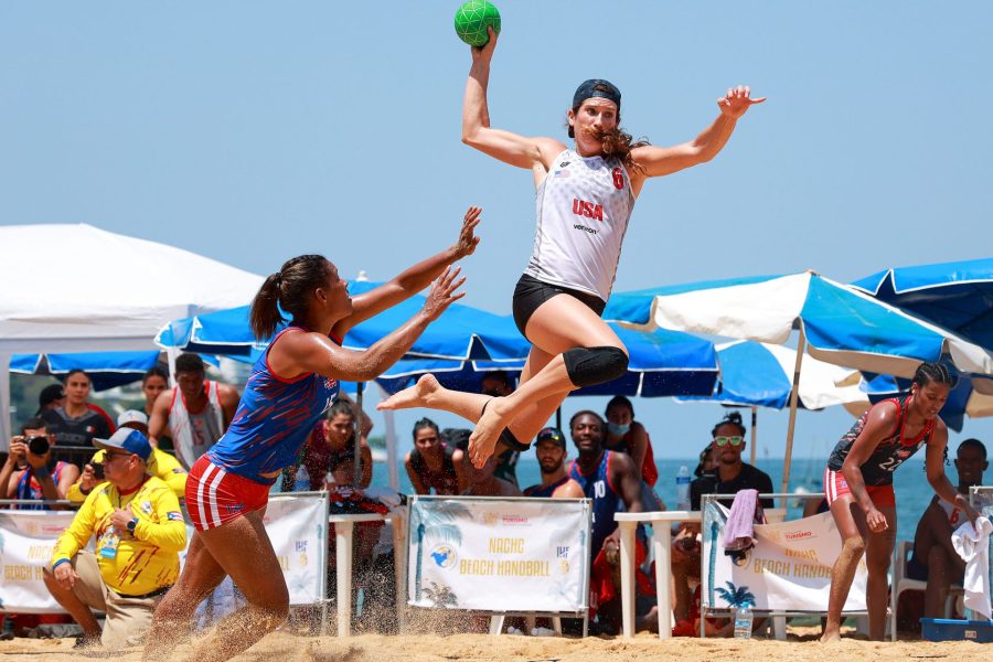 Christine Mansour leaps with a green ball to avoid an opponent.