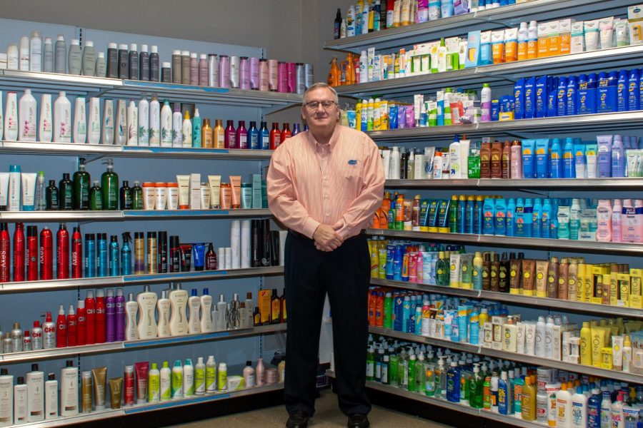 Chip Lane stands in front of hair and sun care products on a mock retail store shelf.