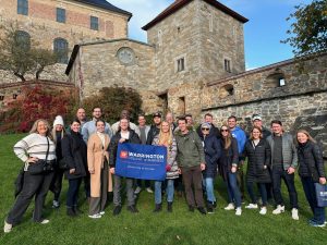 Students on a walking tour in Oslo, hold a UF Warrington College of Business flag.