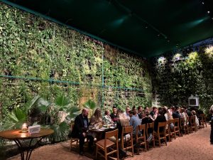 A long table with many people seated along the length eating a meal