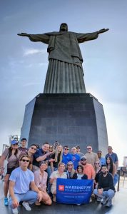 MBA students pose with Christ the Redeemer statue in Brazil and holding the UF Warrington College of Business flag.