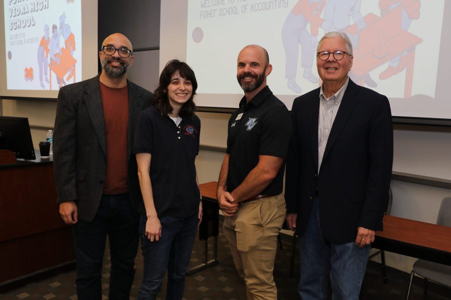 Faculty and friends pose next to a slide presentation.