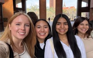 Four female students pose for a selfie on campus.