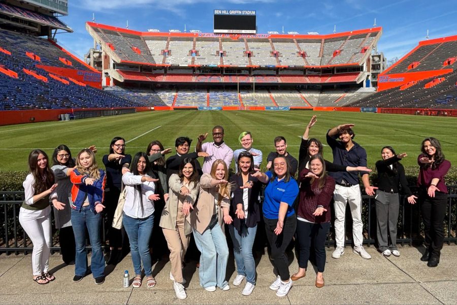 A group of about 20 students do the Gator chomp in Ben Hill Griffin Stadium.