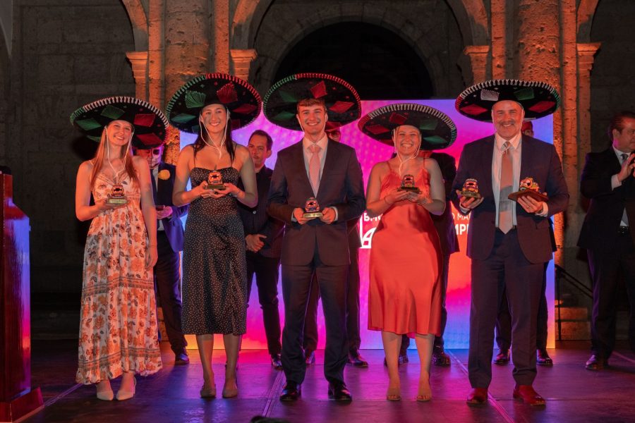 Four students and their teacher pose with trophies and wear sombreros after winning a case competition in Mexico.