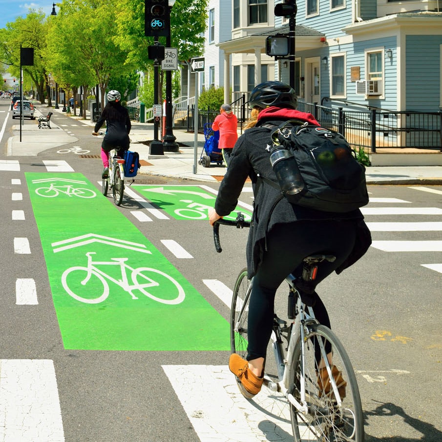 Bicycle riders on a designated bicycle path between a street and sidewalk