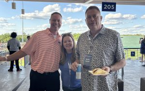 Three people wearing Gator gear pose for a photo at a baseball game during DBA Alumni Weekend.