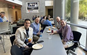 Four men sit at a table while eating lunch during DBA Alumni Weekend.