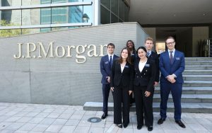 Six students wearing professional attire stand in front of the JPMorgan office sign in South Florida.