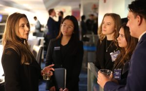 An alumna speaks with four students during a networking reception.
