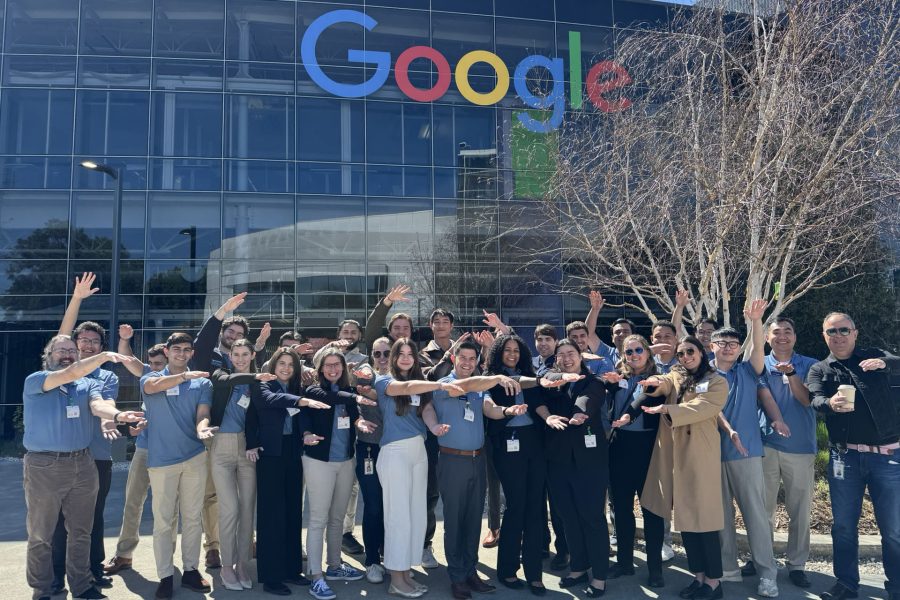 A group of about 20 students do the Gator Chomp in front of Google's office.