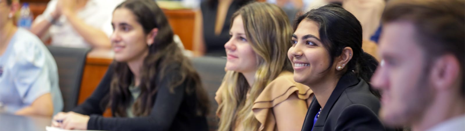 Students attentively listen and smile during a finance seminar at the Warrington College of Business.