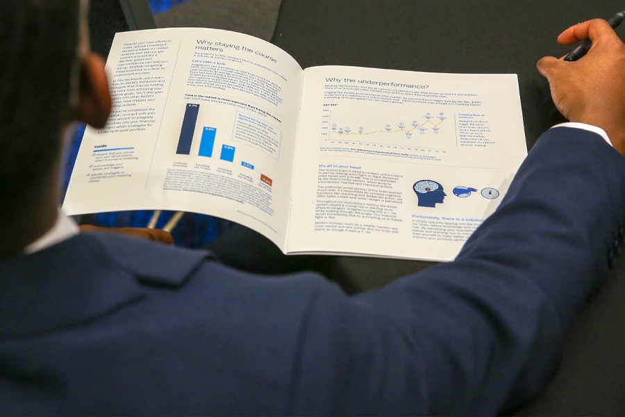 A student in a navy suit reviews a professionally designed financial report featuring charts, graphs, and behavioral finance insights.