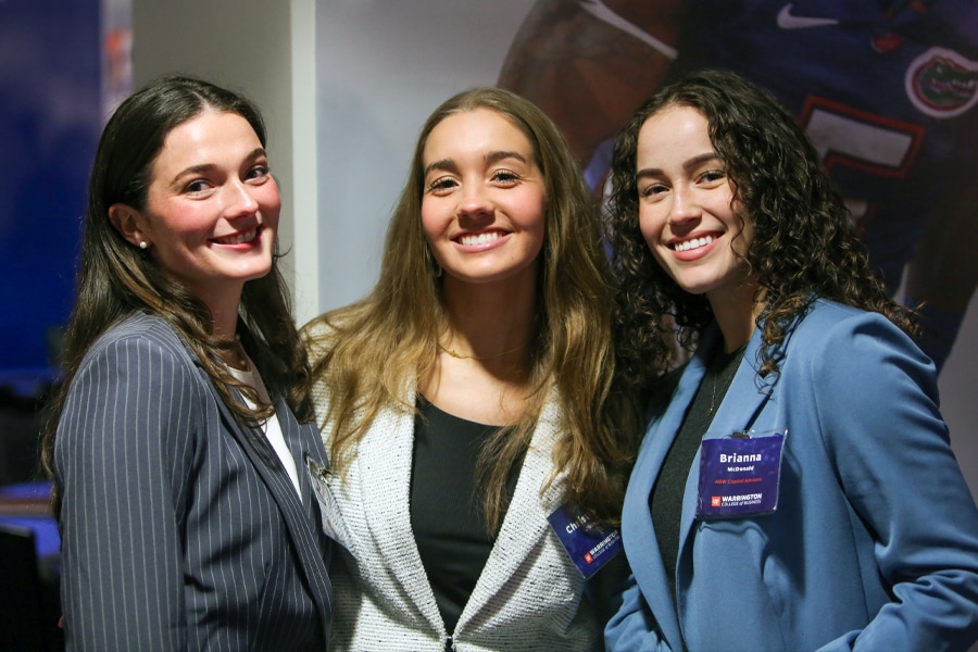 Three undergraduate women dressed in professional attire smile together at the Future Advisor Conference.