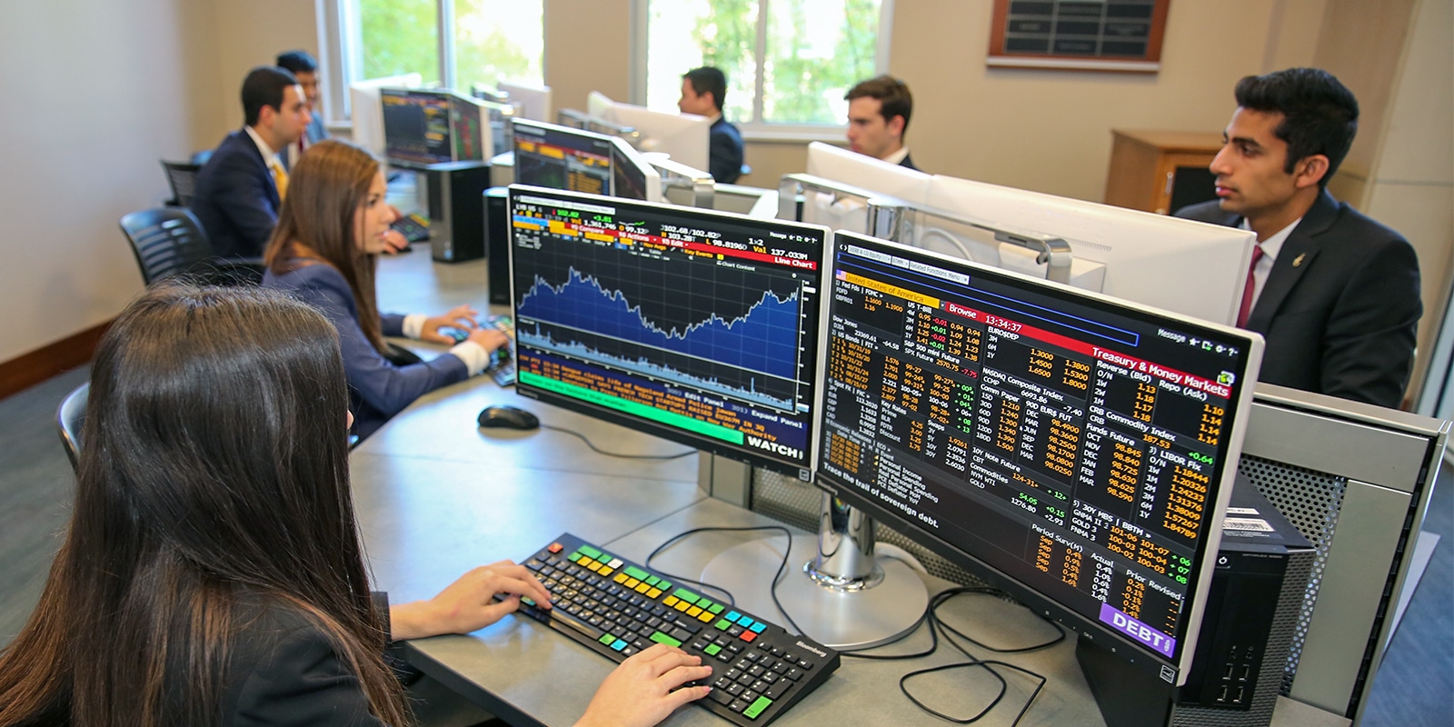 Students in the Gator Student Investment Fund participate in analyst training at computer workstations, analyzing financial data using Bloomberg terminals. The immersive eight-week program equips first-year analysts with skills in value investing, financial modeling, and equity research.