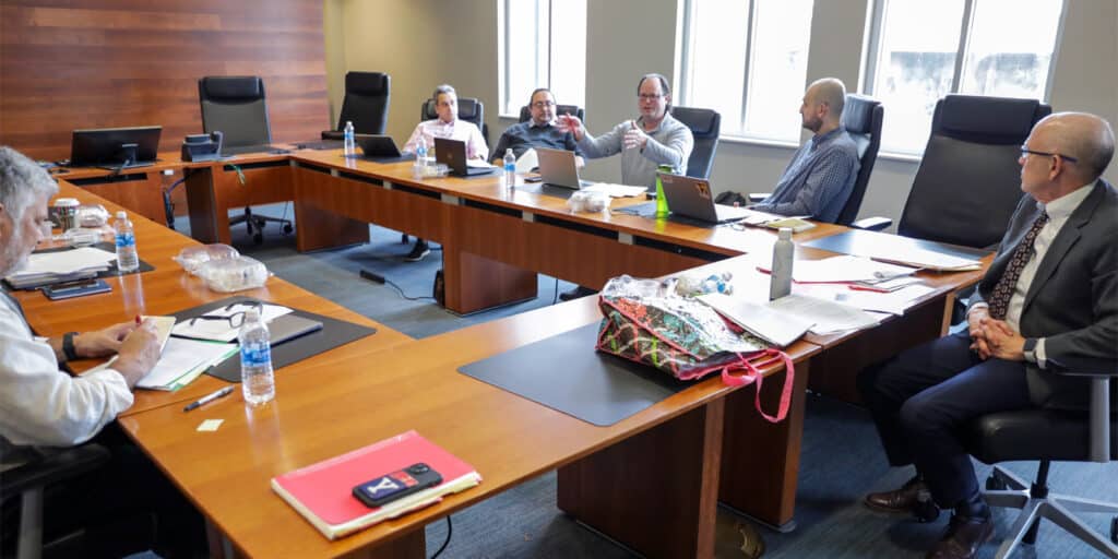 Scholars seated around a large conference table engaged in academic discussion during the Huber Hurst Seminar at the University of Florida Warrington College of Business.