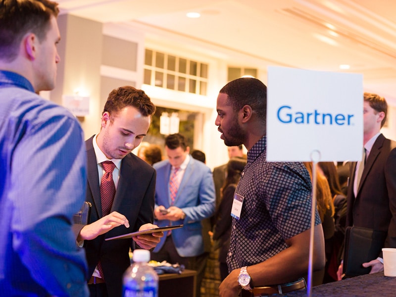 Business man talking to Gartner employees at an event.