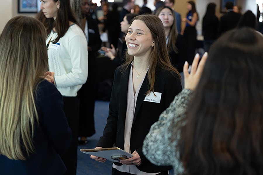 Young woman speaking with a recruiter with other business students around her.