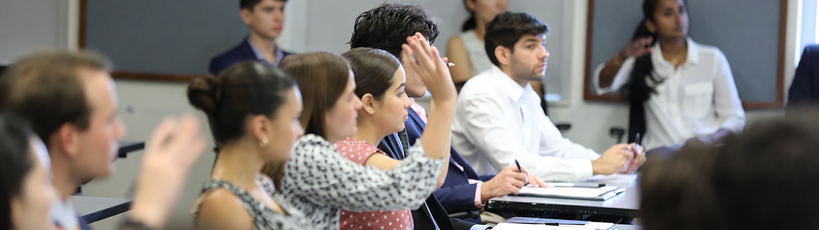A student raises their hand in a classroom for the University of Florida Warrington College of Business' MS Marketing program