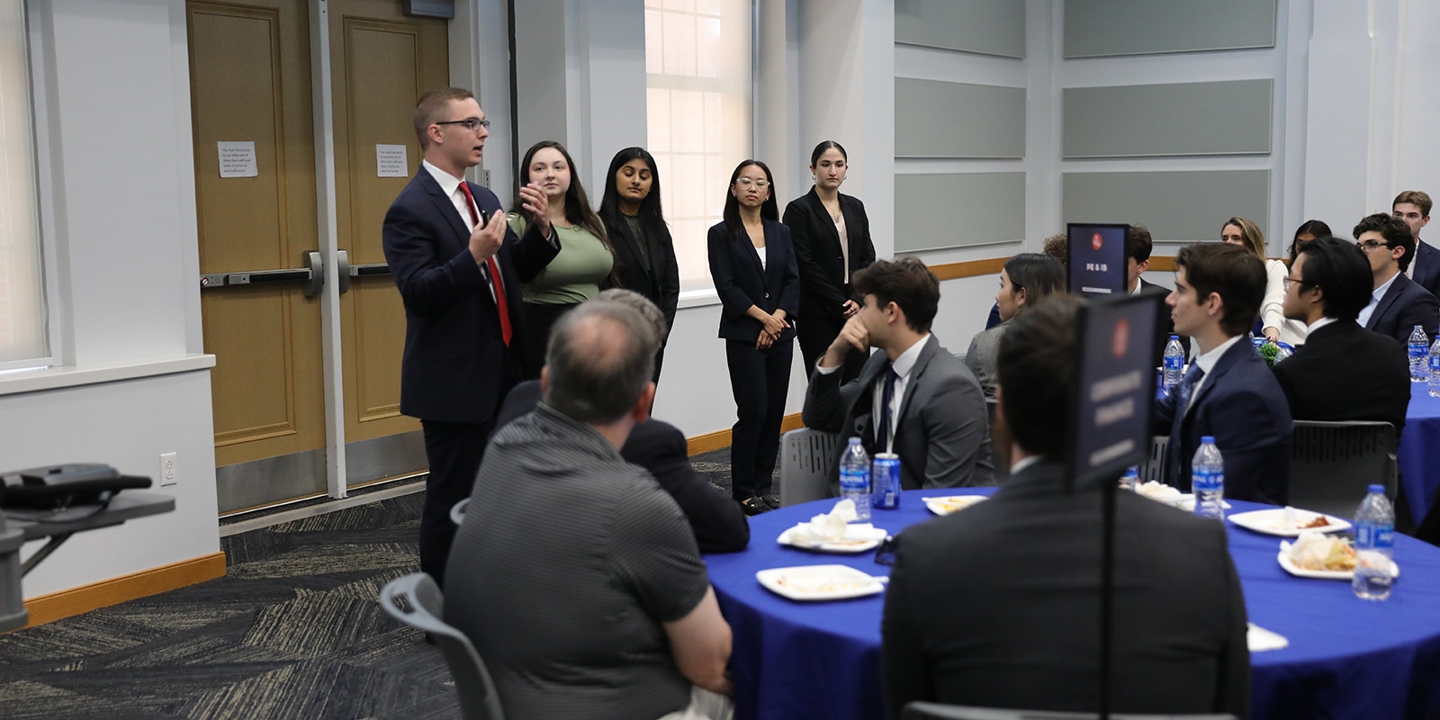 A group of MS Marketing students talk about their GatorNest consulting project to a room full of UF Warrington students and instructors who are sitting at tables
