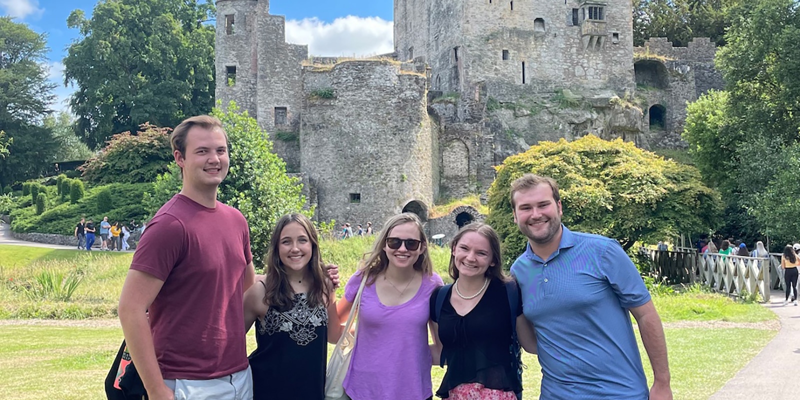 A group of MS Marketing students participating in a study abroad trip with one of UF Warrington's partners lock arms in front of a castle
