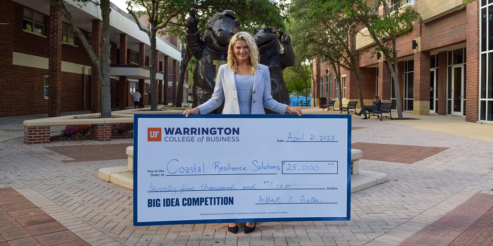 The winner of University of Florida's Big Idea Plan Competition, open to Online MS in Entrepreneurship students, stands while holding a large check