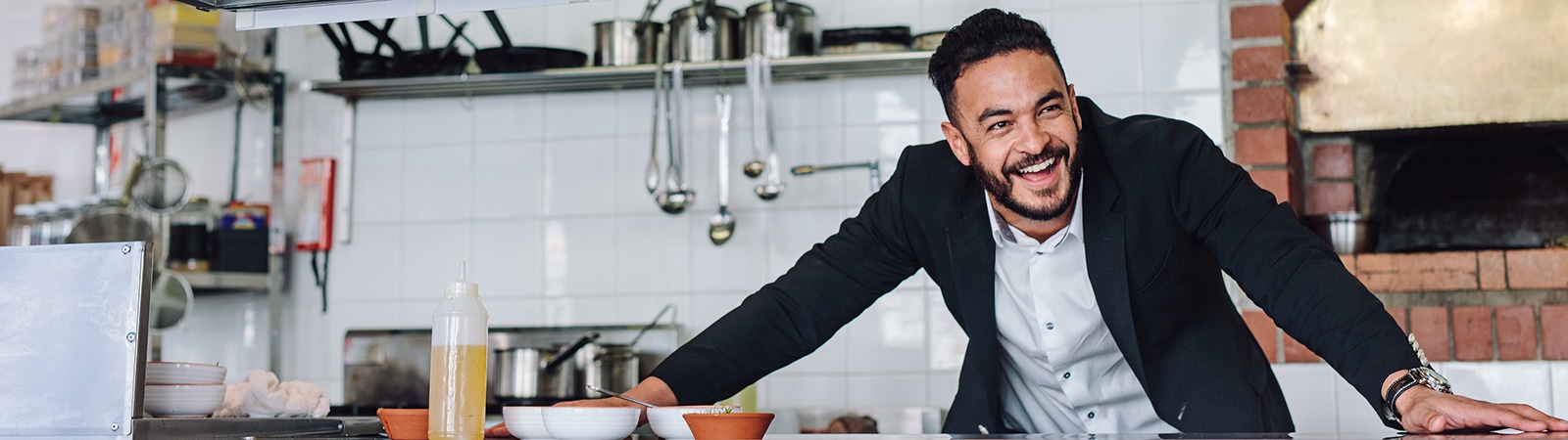 A student from UF Warrington's Online MS in Entrepreneurship program stands with their arms spread on a counter inside a kitchen