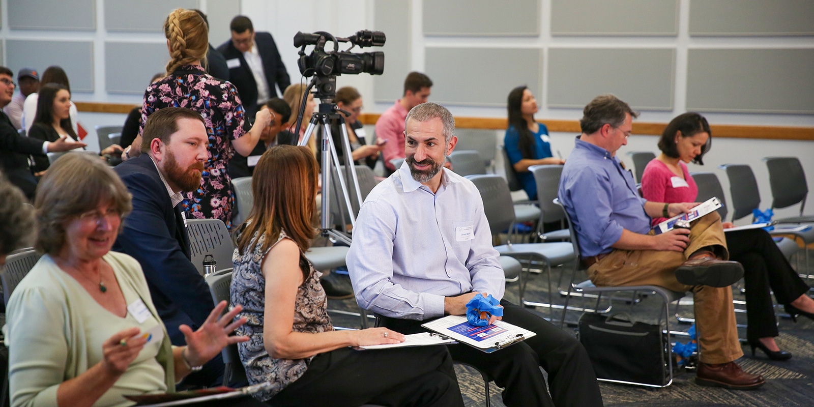 Online MS in Entrepreneurship and other University of Florida students hold brochures while waiting for a presentation for the Lean Entrepreneurship Accelerator Program to begin