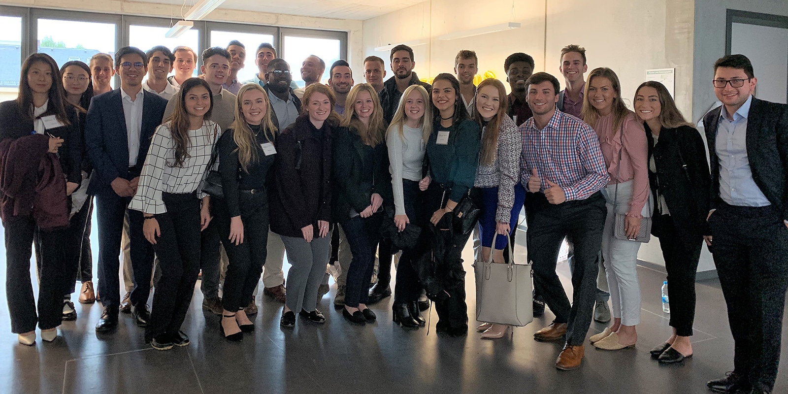 A large group of students from UF Warrington's MS Marketing program pose for a photo in a corporate building during their Global Immersion Experience