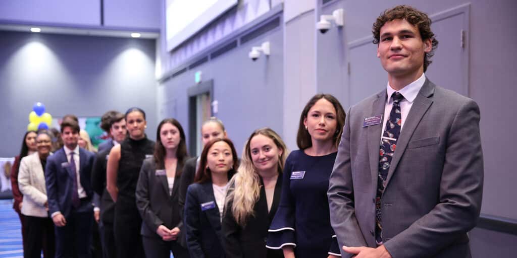UF Warrington BSBA in Marketing students in suits stand in a line as they tour an organization 