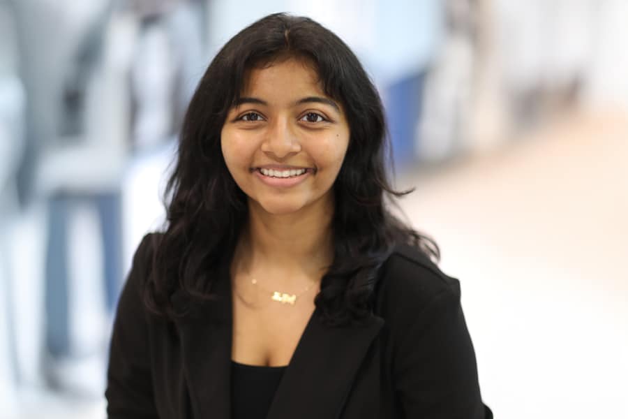 Dhruvi Patel, VP of External Operations for Business Ethics Ambassadors, smiles in a professional headshot with shoulder-length dark hair and a black blazer.