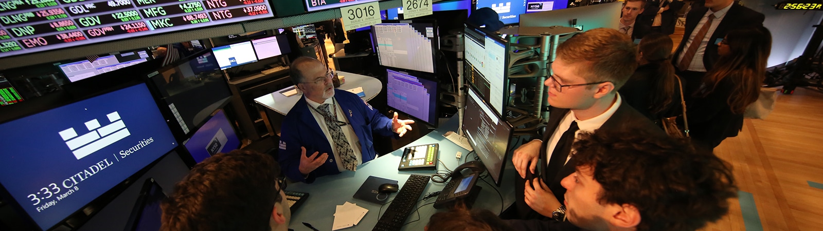 A group of students listen to a stock trader.