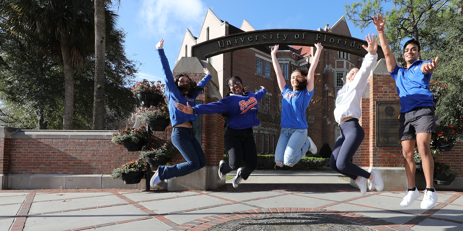 Happy students in action in front of the University of Florida gateway. 