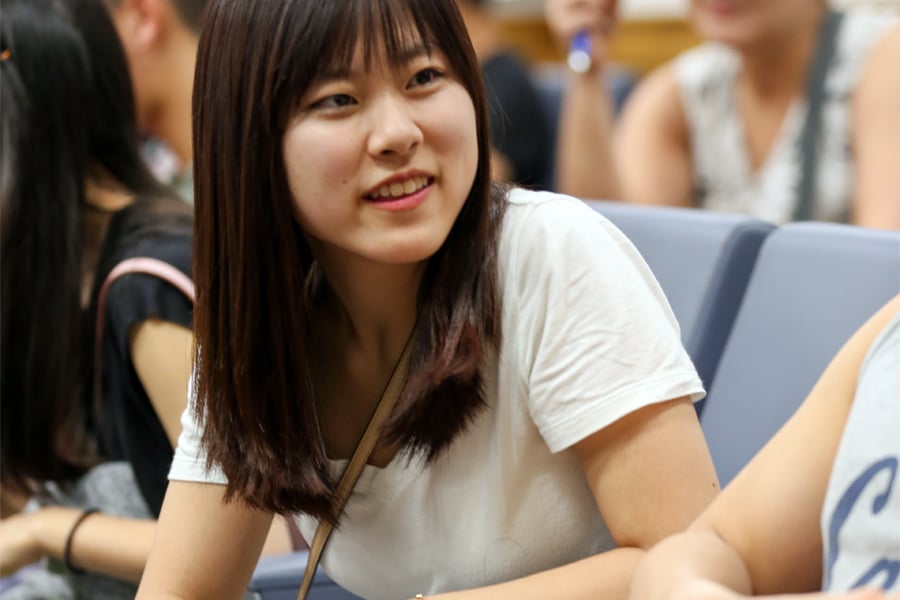 An attentive international student listens carefully in a conference or classroom setting during an event.