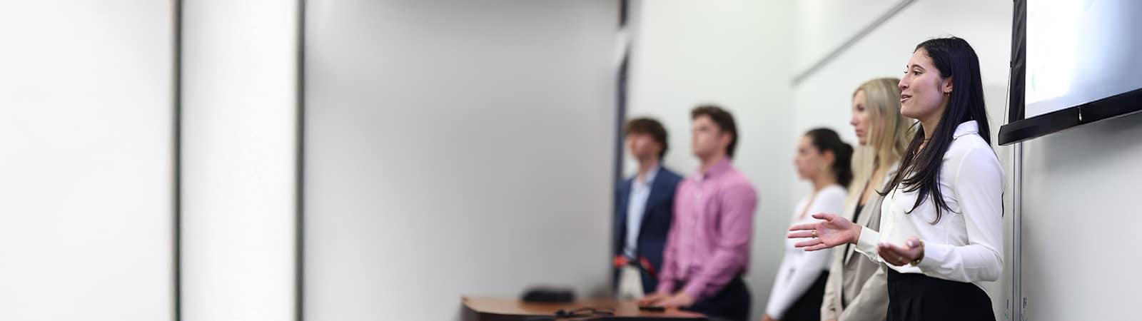 Female student confidently speaking during a group presentation.