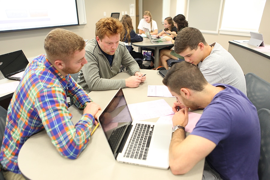 Group of students working on a project around a table. 